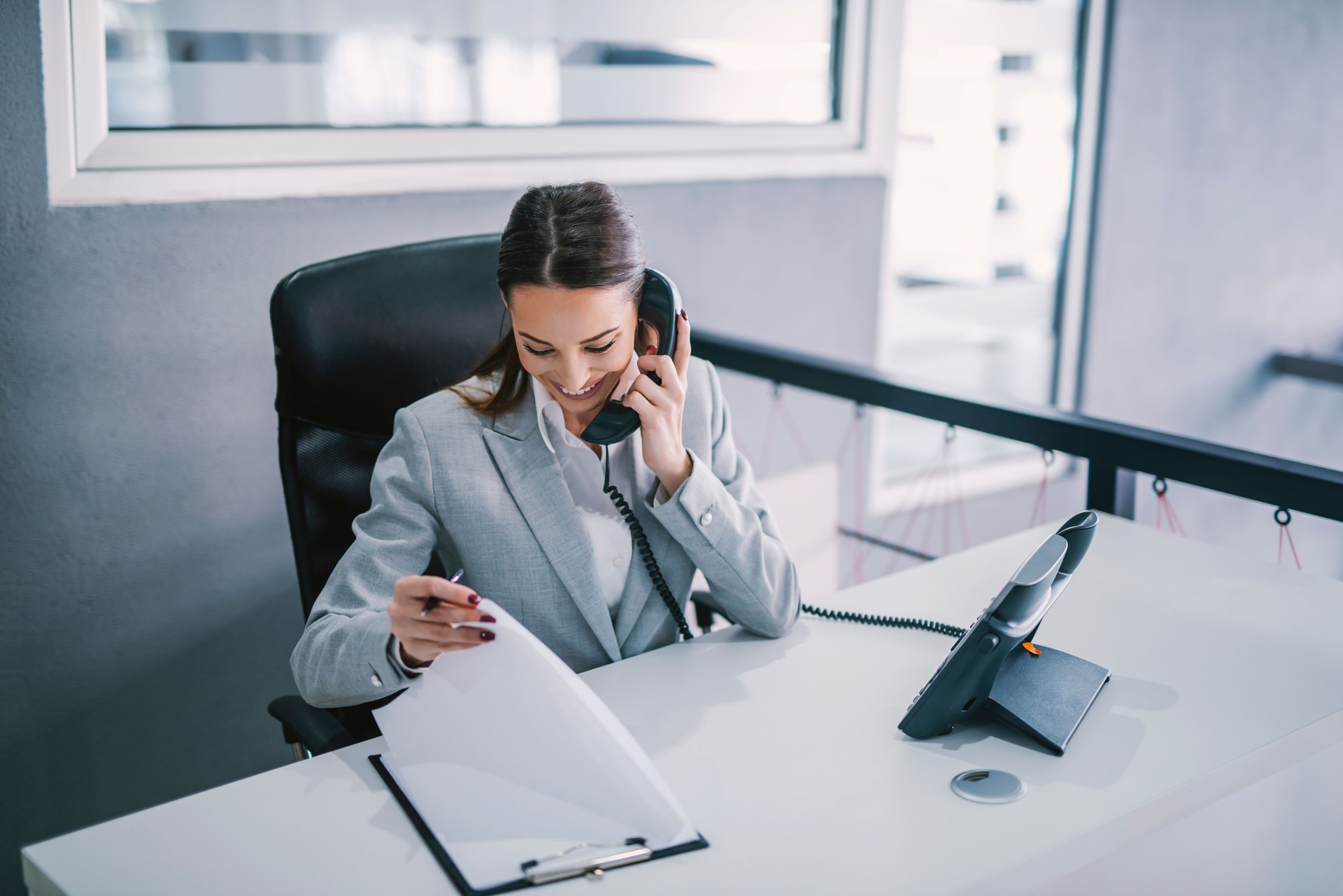 An assistant schedules a meeting on the phone at modern office.